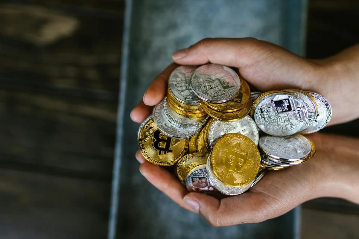 A close-up of hands holding various cryptocurrency coins, representing digital finance.