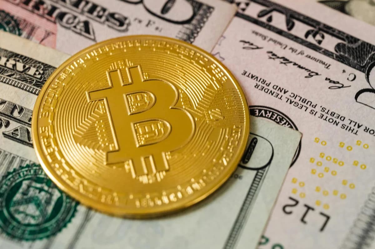 A detailed view of a Bitcoin coin resting on US dollar bills, symbolizing modern finance.