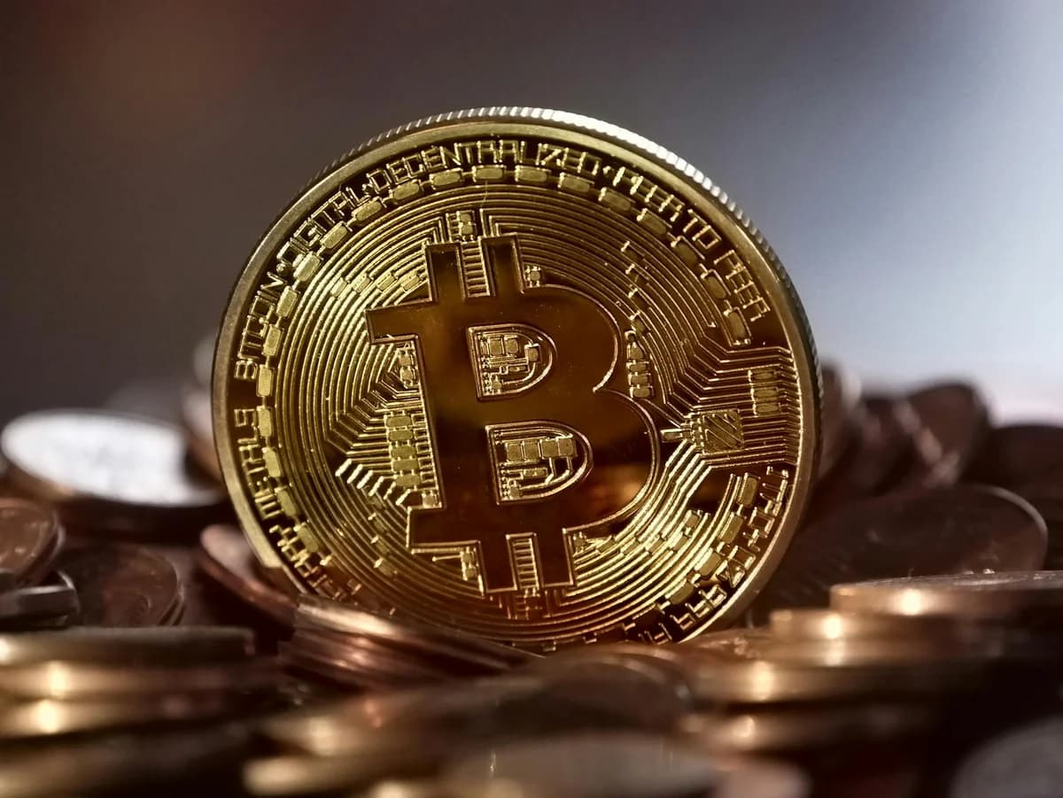 Close-up of gold Bitcoin coins on a trading document, symbolizing investment and cryptocurrency market strategies.