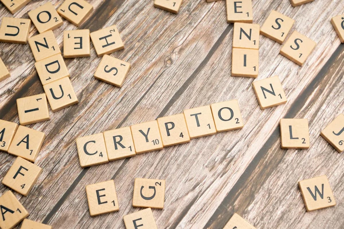 Wooden letter tiles spelling 'Crypto' creatively arranged on a rustic wood surface.