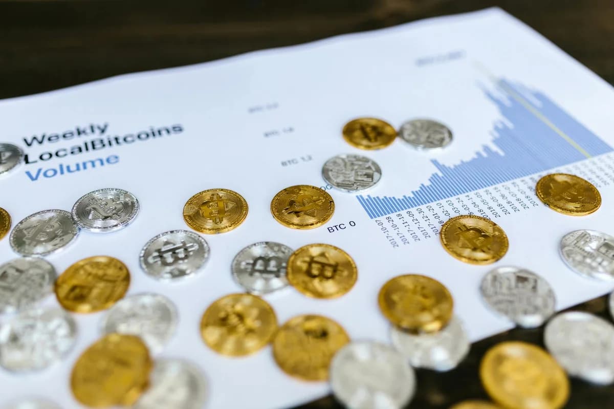 A collection of cryptocurrency coins and a smartphone displaying a digital trading platform.