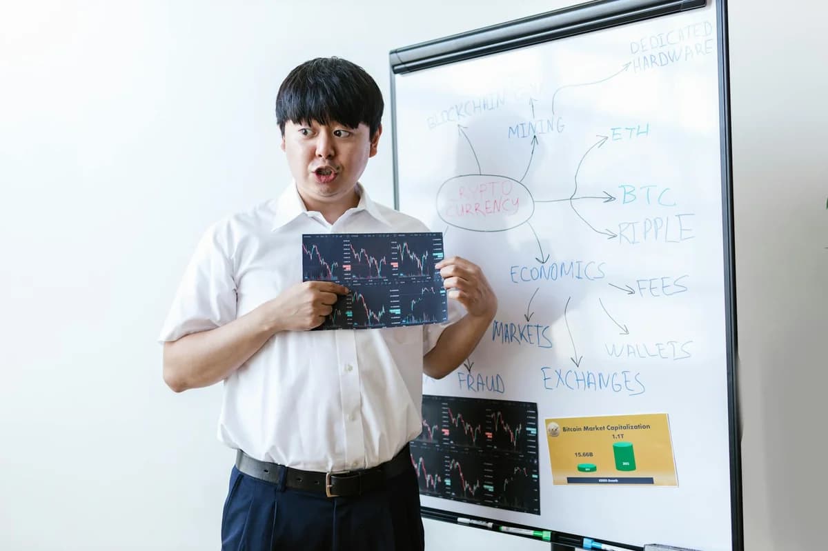A man presenting cryptocurrency concepts on a whiteboard with charts and graphs.