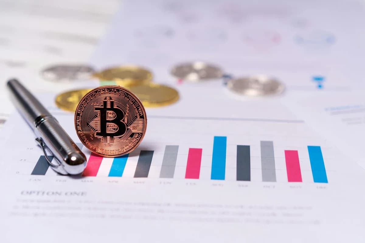 Bitcoin coins placed on a laptop keyboard with sticky note reminders about investing and checking new coins.