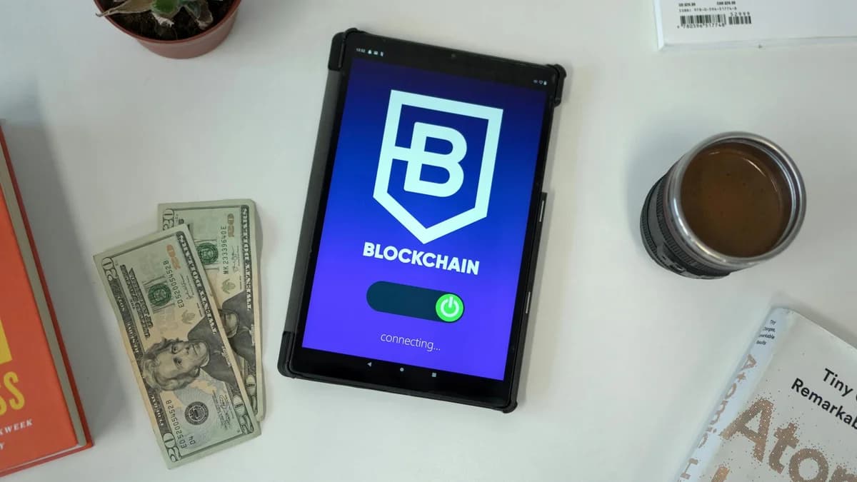 A laptop displaying blockchain technology in a modern workspace with books and headphones.