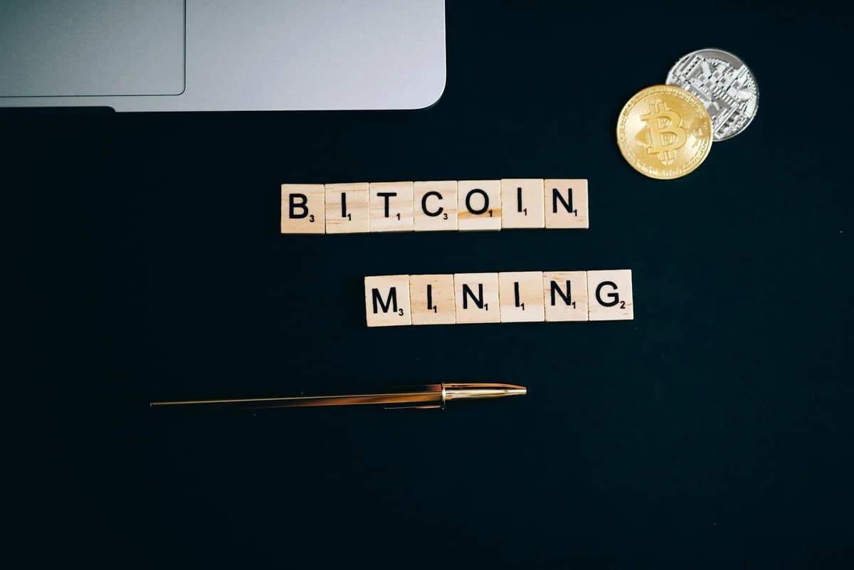 Overhead view of Bitcoin mining concept with coins and Scrabble tiles on black surface.