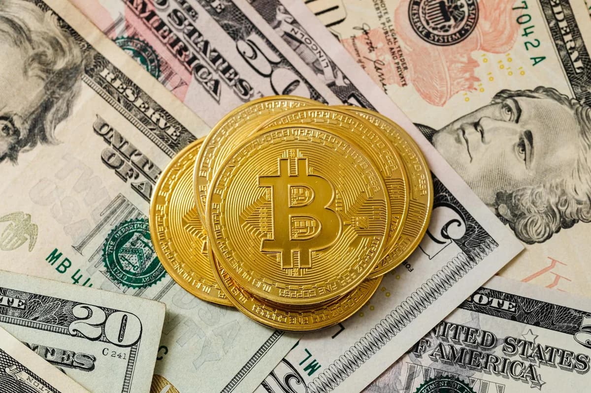 Close-up of gold bitcoin coins on US paper money, representing cryptocurrency investment.