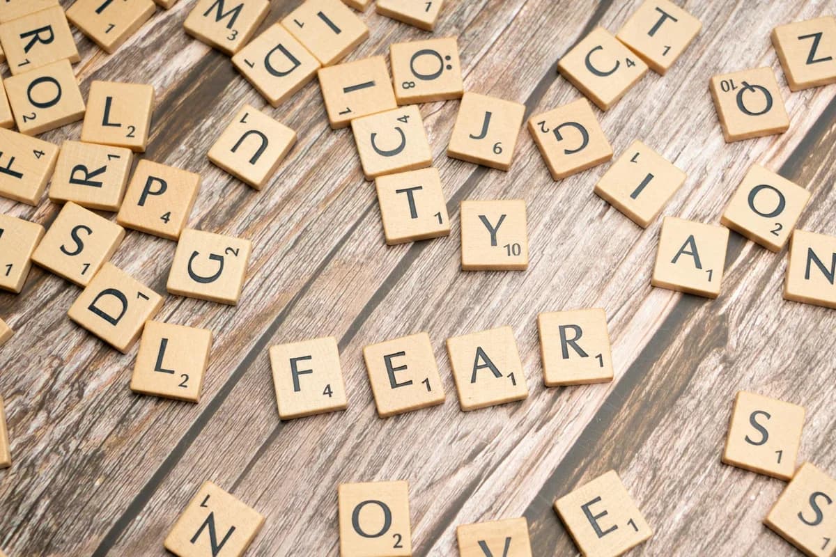 Scrabble tiles on wood surface spelling 'fear', representing emotions like dread and anxiety.
