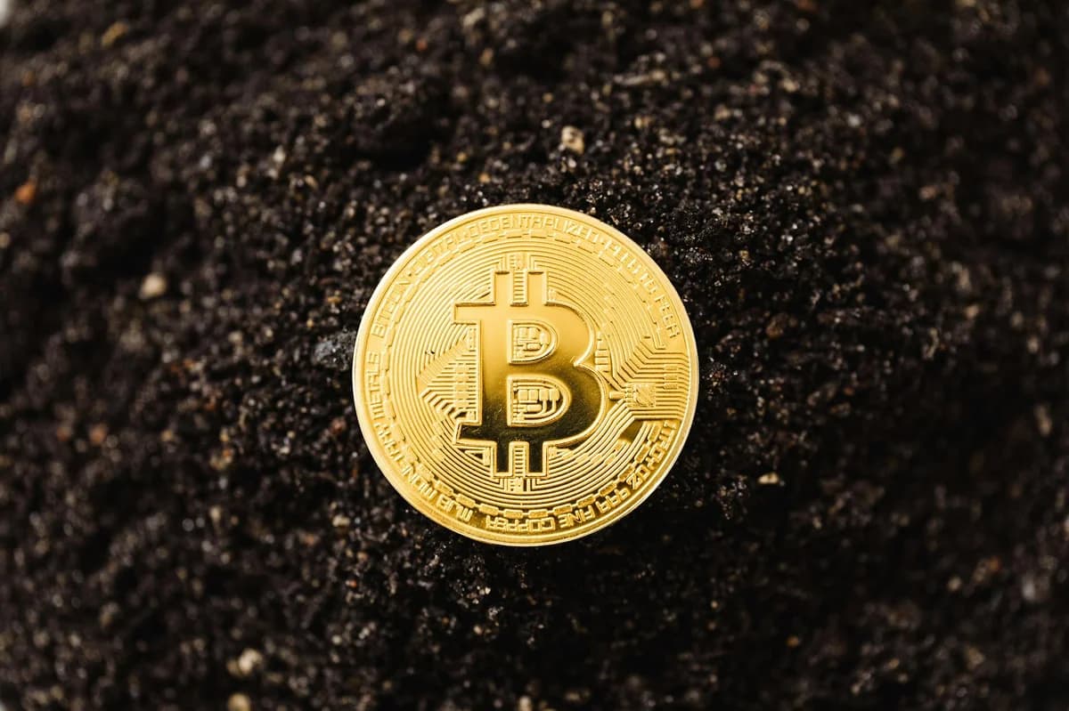 Overhead view of Bitcoin mining concept with coins and Scrabble tiles on black surface.
