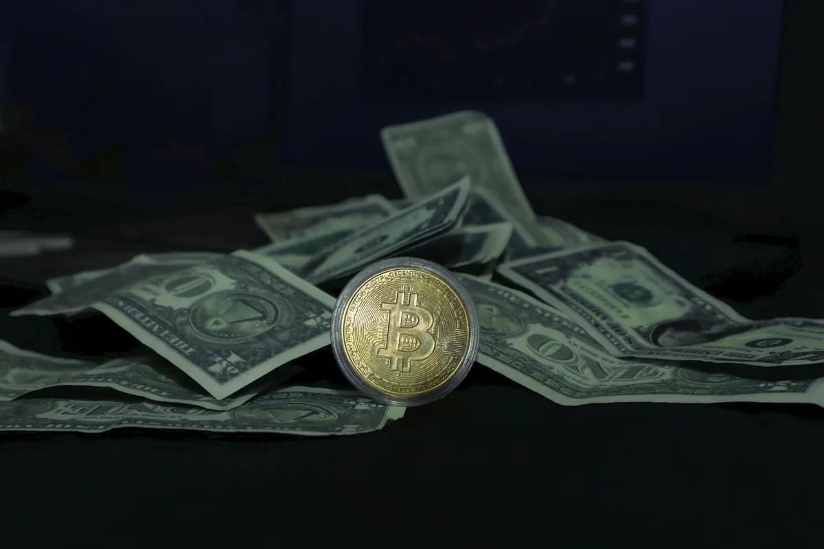 Close-up of a Bitcoin coin and US dollar bills, highlighting cryptocurrency and finance.