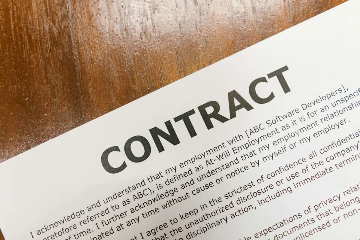 Close-up of a contract document alongside a smartphone and laptop, ideal for business concepts.