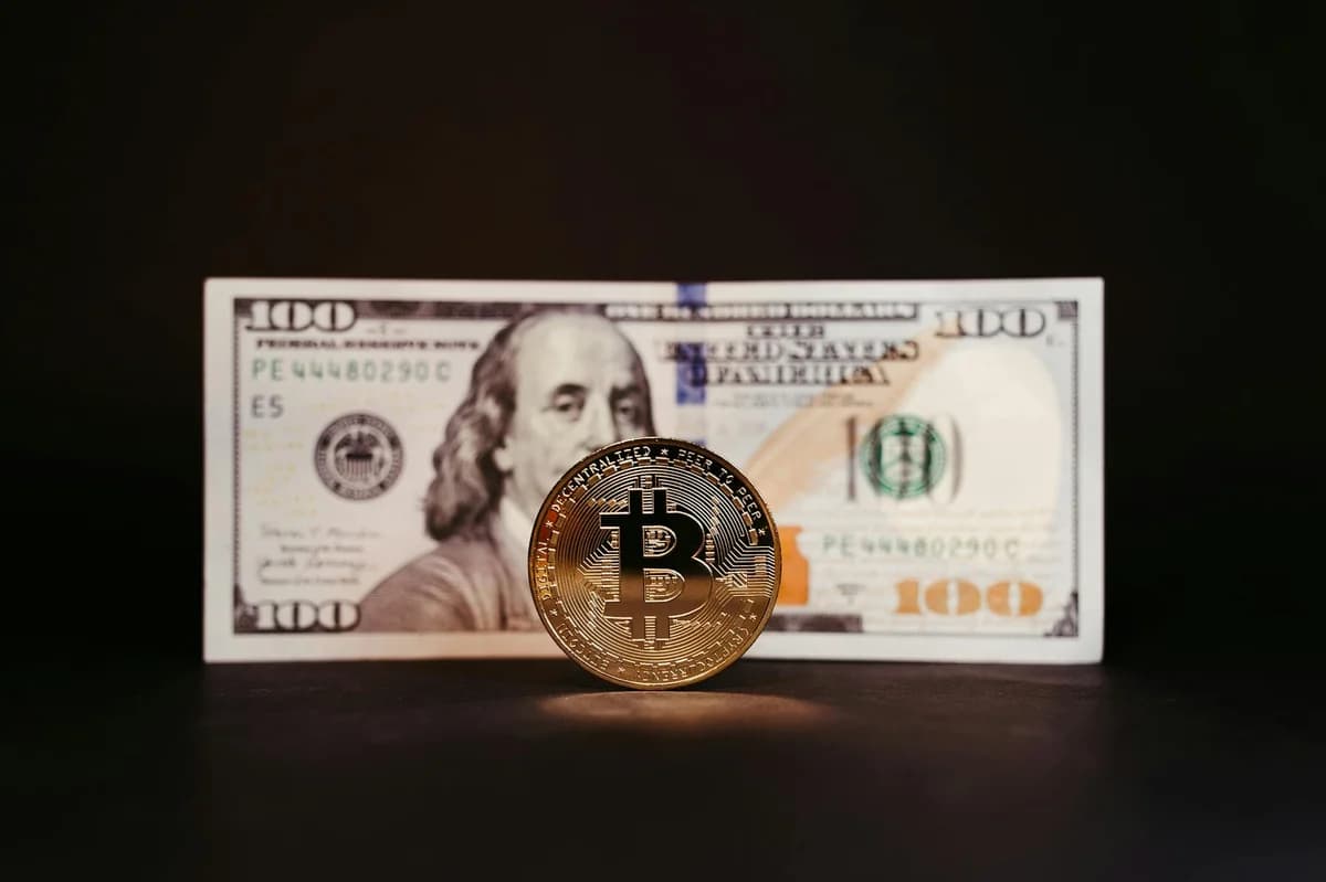 Close-up of a gold Bitcoin coin placed on various US dollar bills, illustrating digital currency concepts.