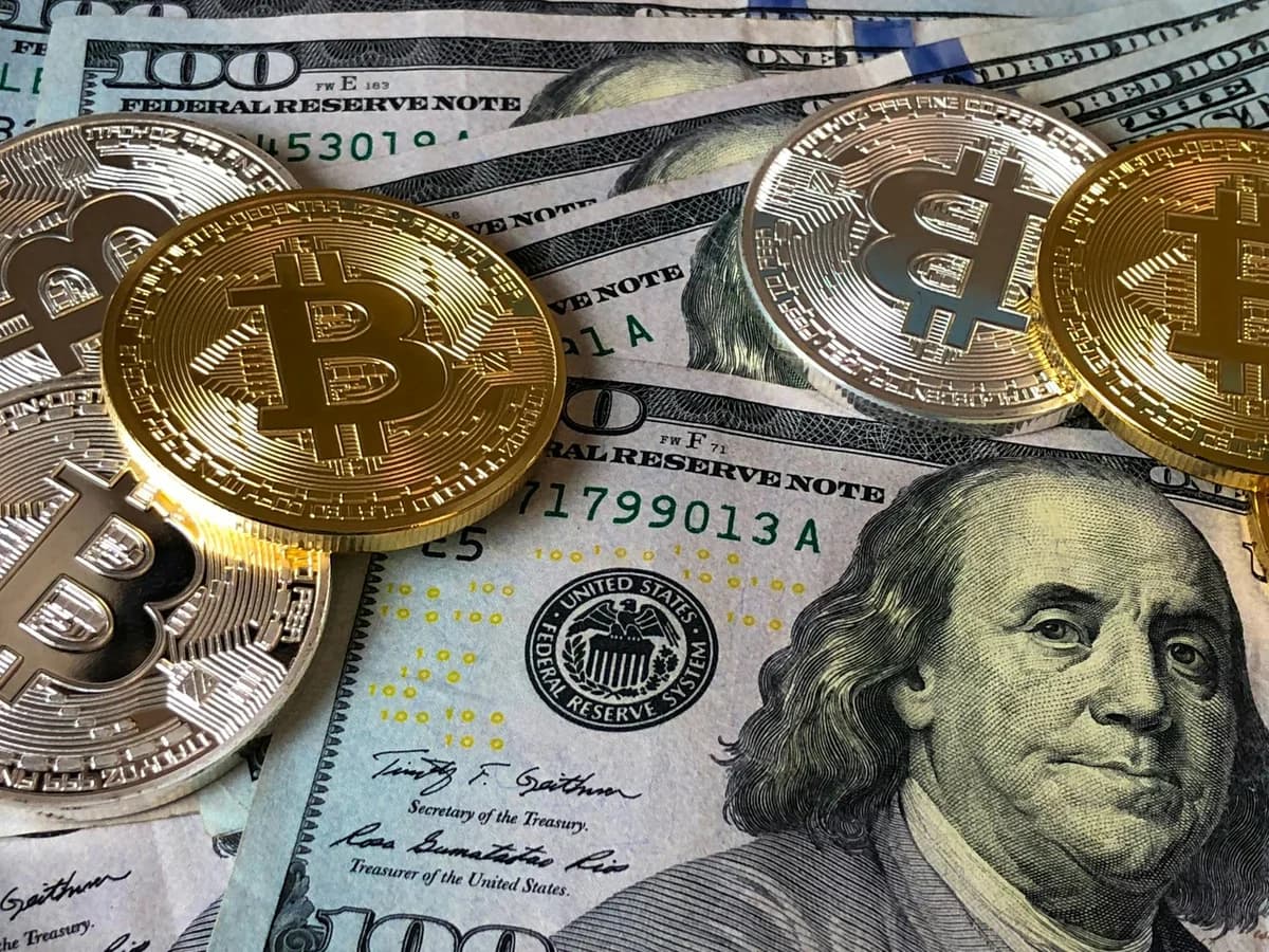 Bitcoin coin on US dollar bills with a stock market chart background. Represents cryptocurrency and finance.