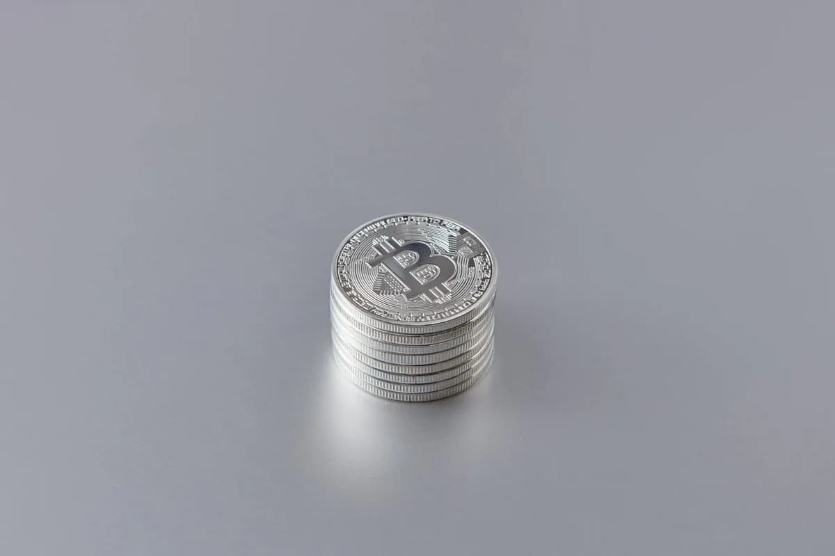 Close-up of silver Bitcoin coins stacked on a gray surface, showcasing cryptocurrency technology.