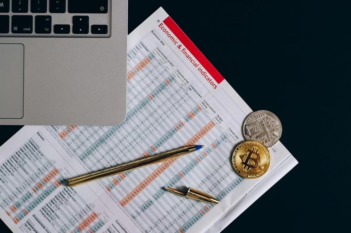 Top view of a laptop, Bitcoin coins, and financial indicators symbolizing Bitcoin mining and investment.
