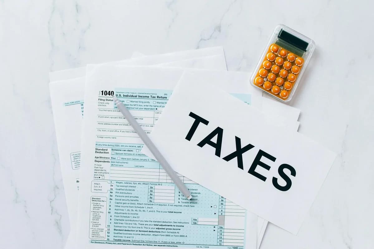 Flat lay of tax form, pencils, and calculator on black background, emphasizing tax deductions.