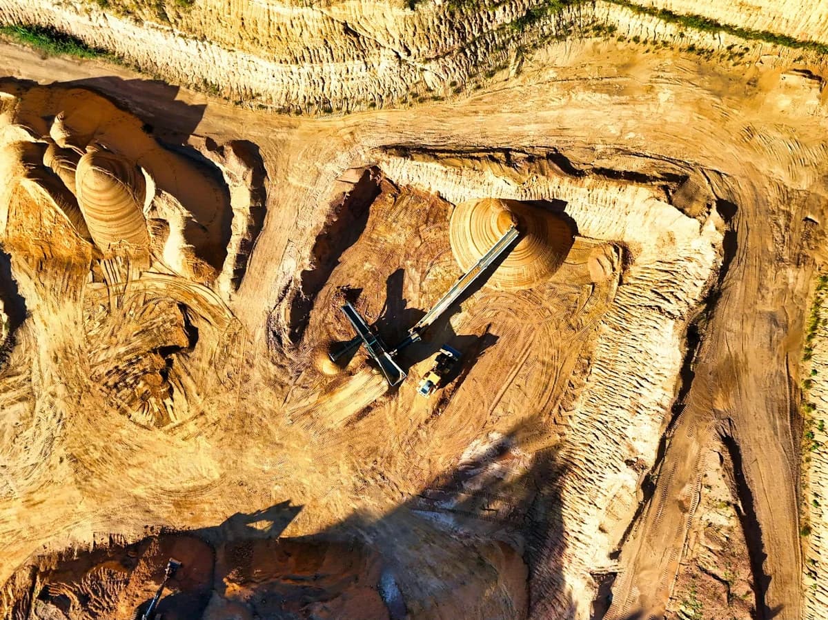 Aerial shot of a vast open-pit mine with visible heavy machinery excavating minerals.