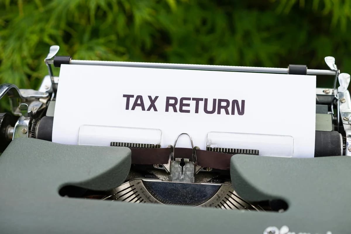 Close-up of tax returns folder beside a stack of American dollars, representing finance and accounting.