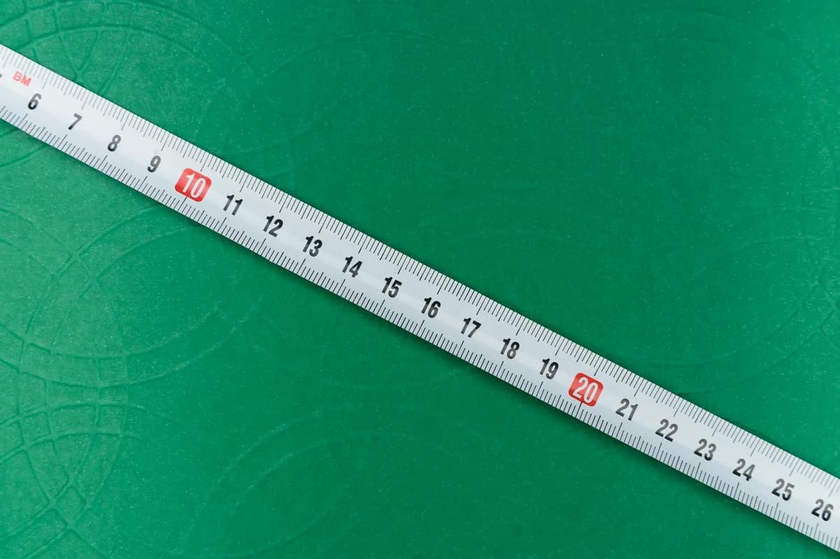 A close-up shot of a tape measure on a textured green background, showing precise measurements.