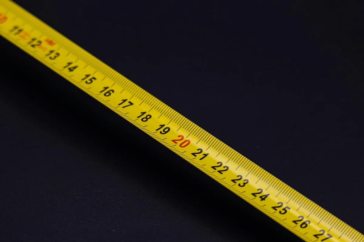 A detailed close-up of a yellow measuring tape against a black background, emphasizing precision and measurement.