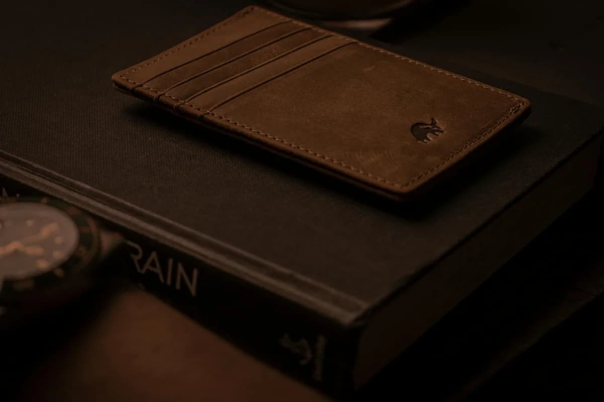 A close-up of hands holding a wallet filled with Polish banknotes on a desk.