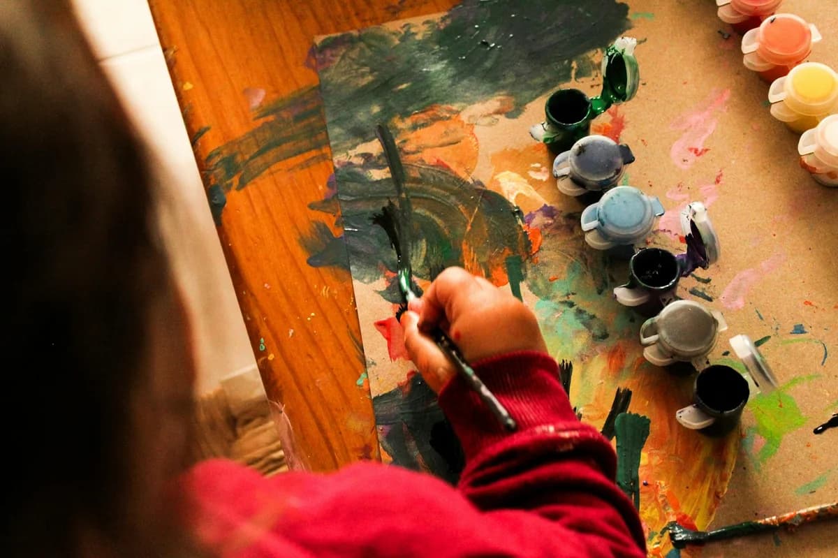 A child creatively paints with various colors indoors, fostering imagination.