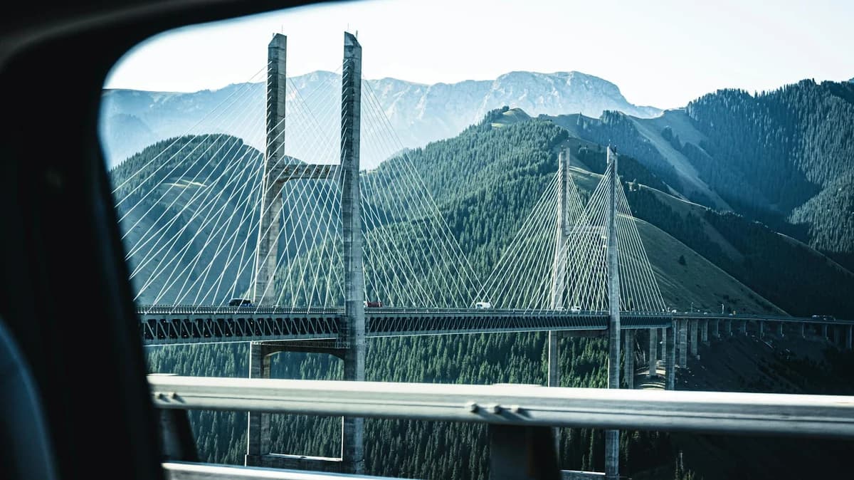 Stunning shot of Guozigou Bridge with mountains in the background, taken from a moving vehicle.