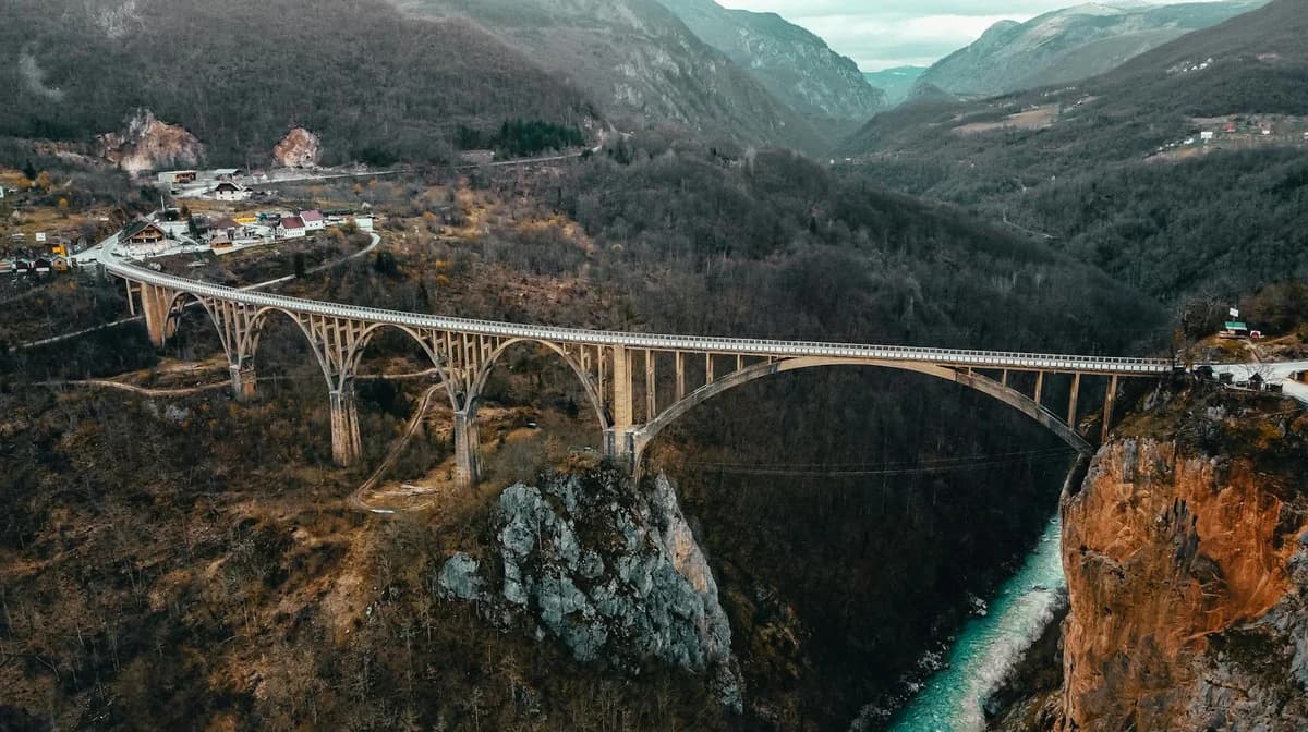Aerial view of Đurđevića Tara Bridge in Montenegro, capturing its grandeur amidst lush fall scenery.