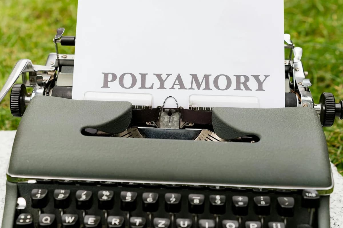 A vintage typewriter displaying the word 'Polyamory' on paper outdoors, ideal for articles on relationships.