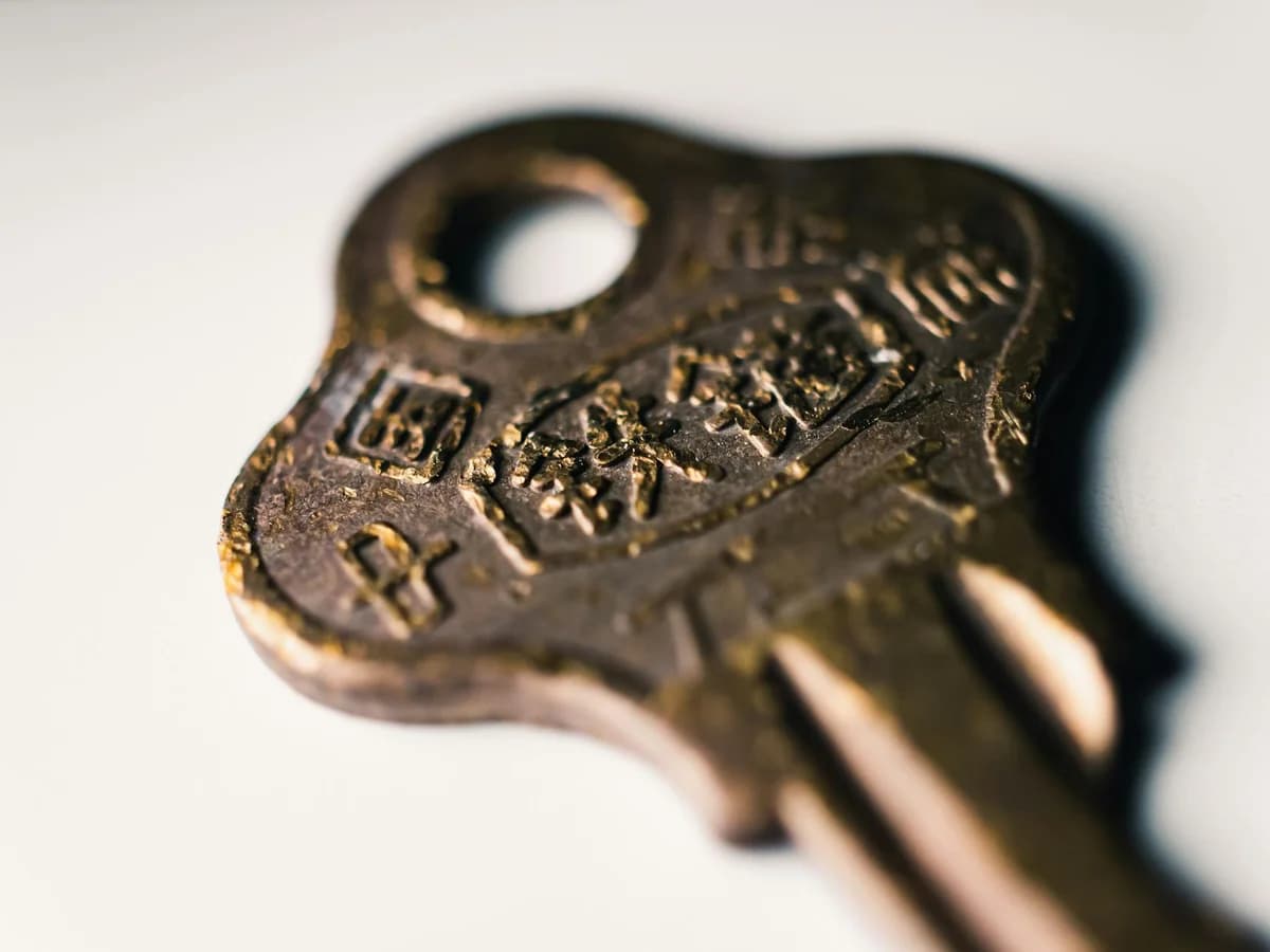 Macro shot of an old brass key featuring worn text on a white surface.