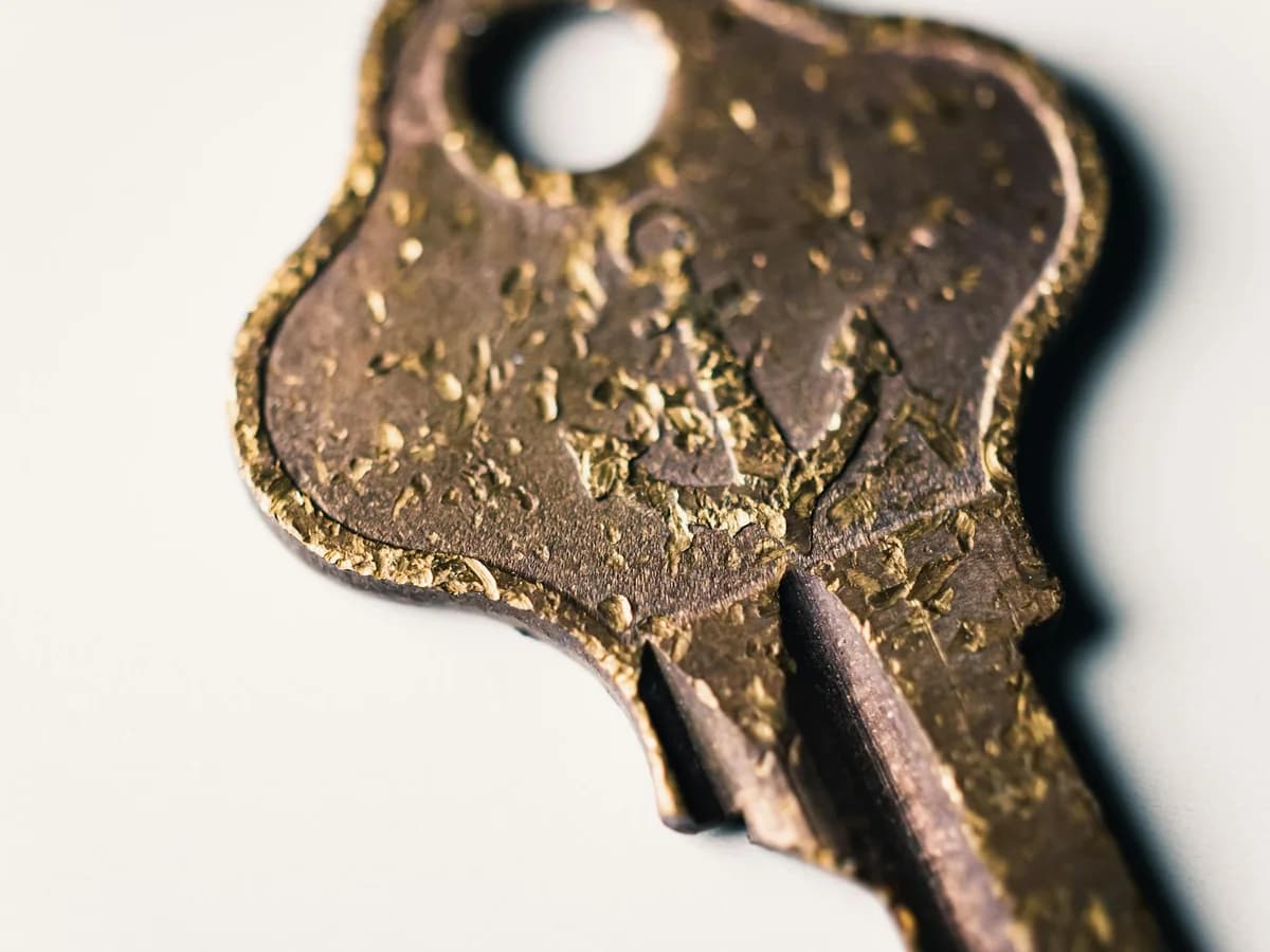Detailed macro shot of a vintage brass key with textured patina, lying on a light background.