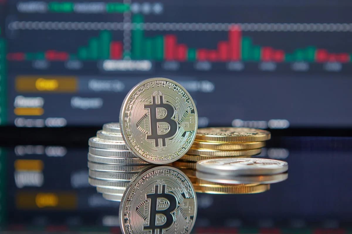 Close-up of Bitcoin coins on reflective surface with financial trading chart, symbolizing cryptocurrency market dynamics.