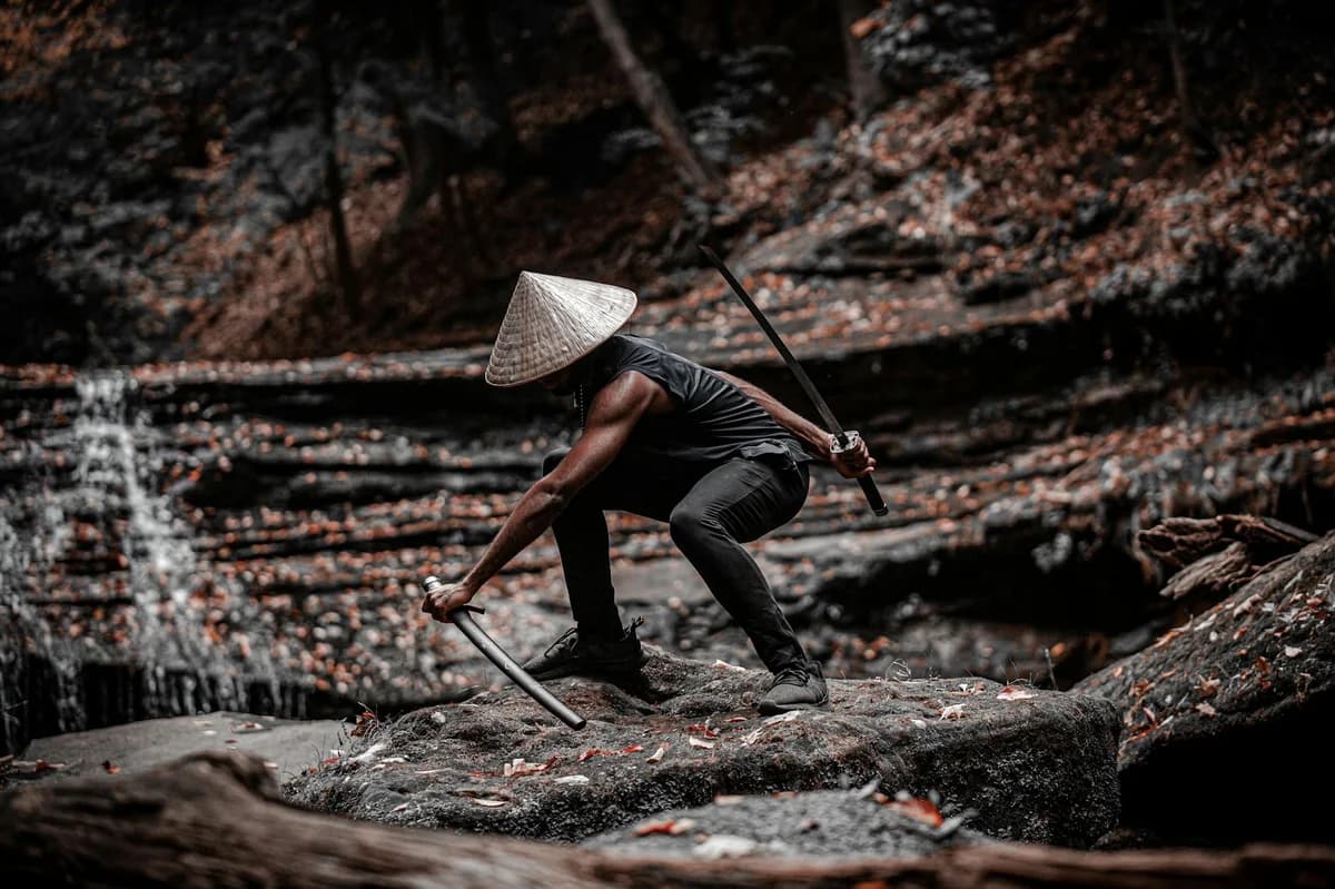A lone samurai crouches with a sword in a serene forest setting, exuding strength and focus.