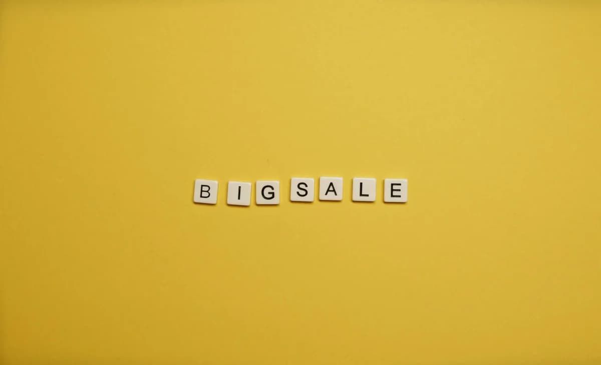 Alphabet tiles spelling 'BIG SALE' on a bright yellow backdrop.