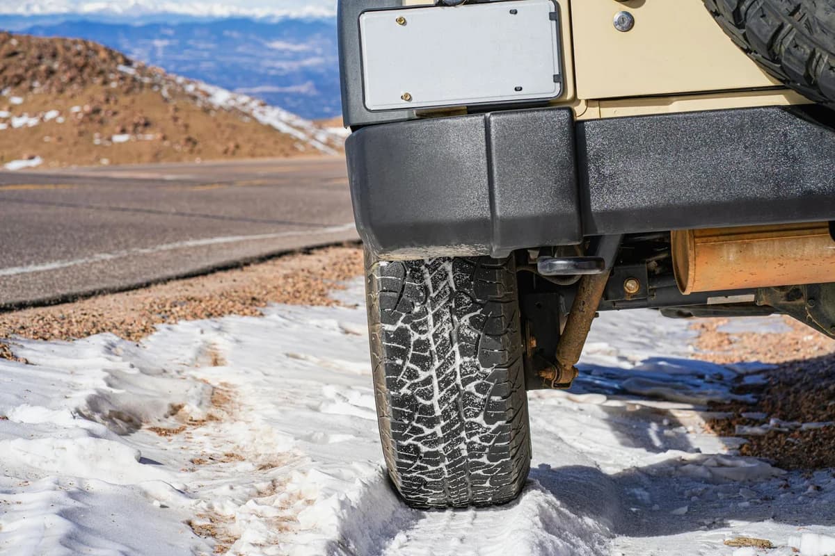 Close-up of an off-road vehicle tire gripping a snowy mountain road in Colorado, showcasing adventure travel.