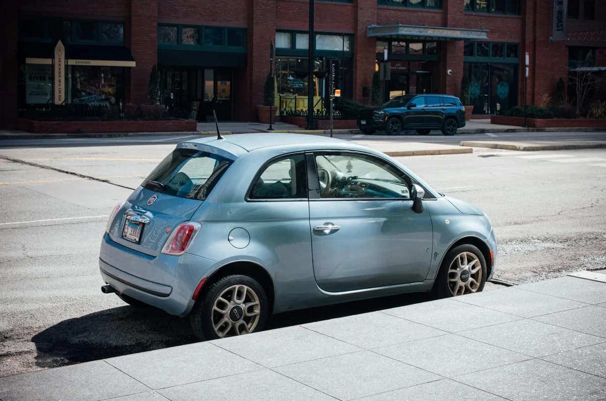 Blue Fiat 500 parked on a Chicago street with brick building backdrop.