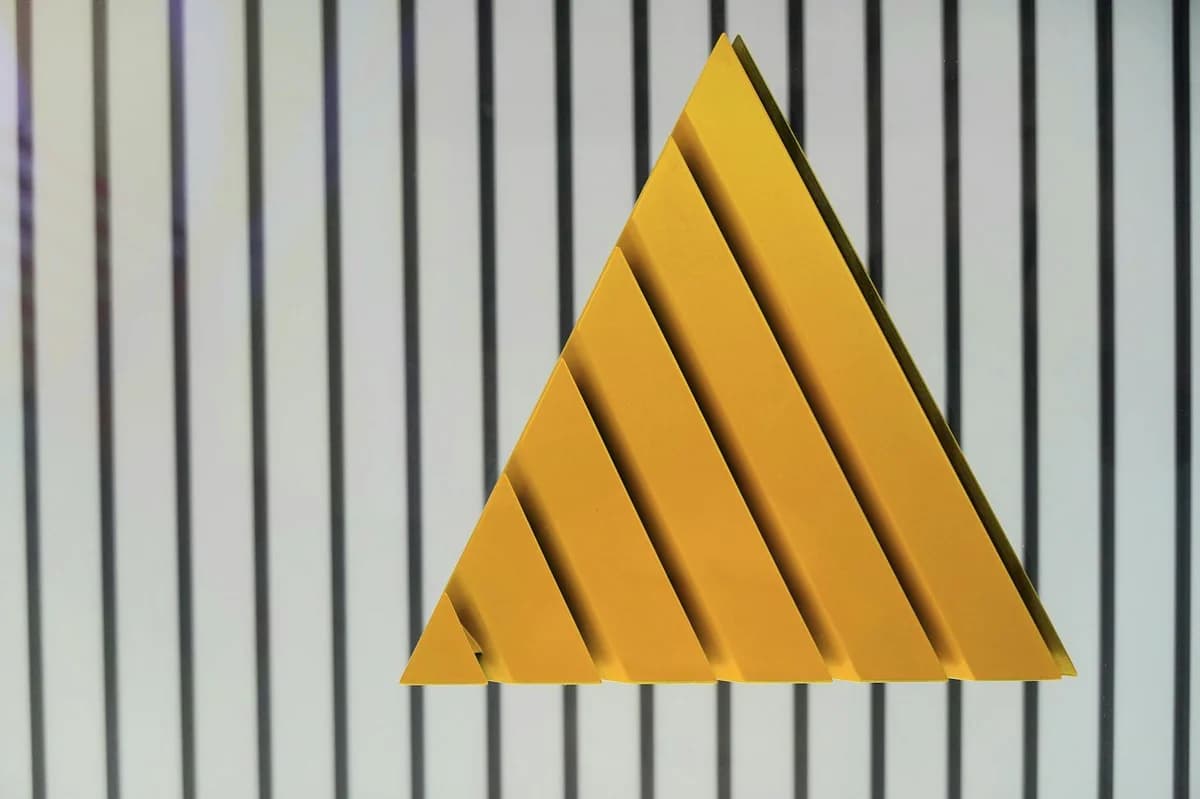 A geometric yellow triangle placed against a black and white striped background, creating an abstract visual.