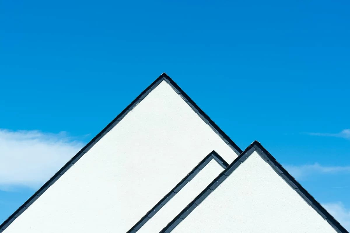 Geometric minimalist photo of white roofs forming striking triangles against a vibrant blue sky.