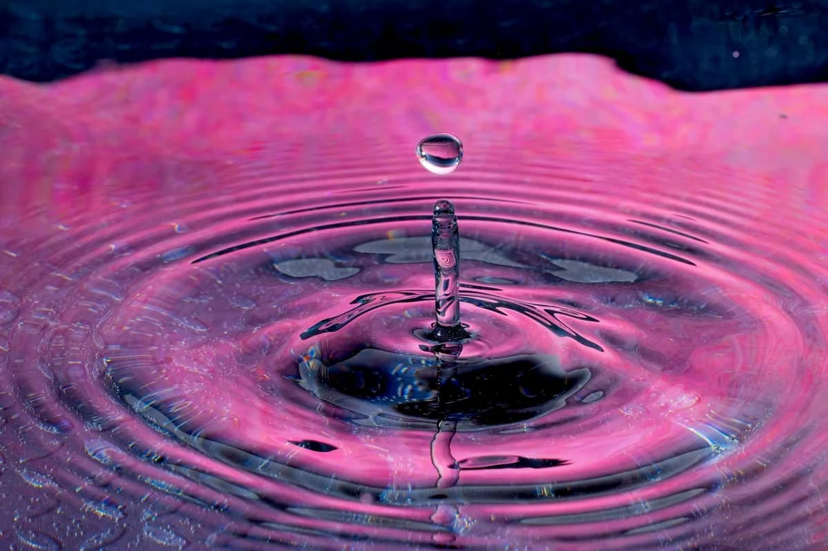High-speed photo of vibrant water droplet creating colorful ripple effect.