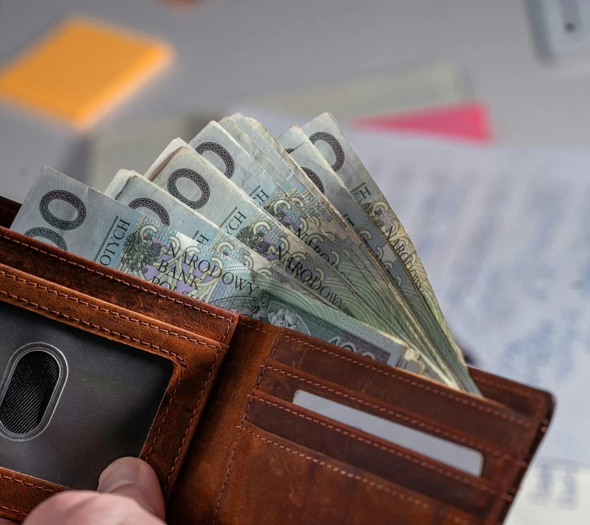 Close-up of financial documents, credit cards, coins, and a pen on a wooden desk.