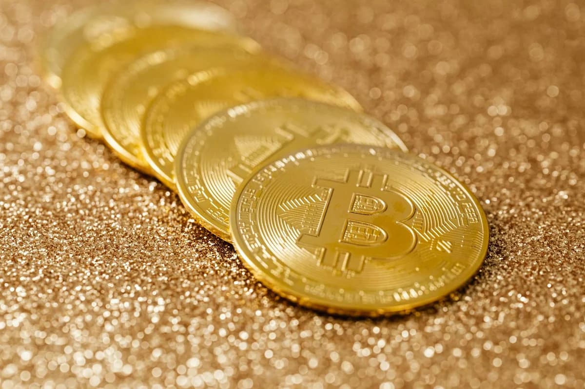 Shiny gold bitcoin coins placed on a textured glitter surface, highlighting cryptocurrency.