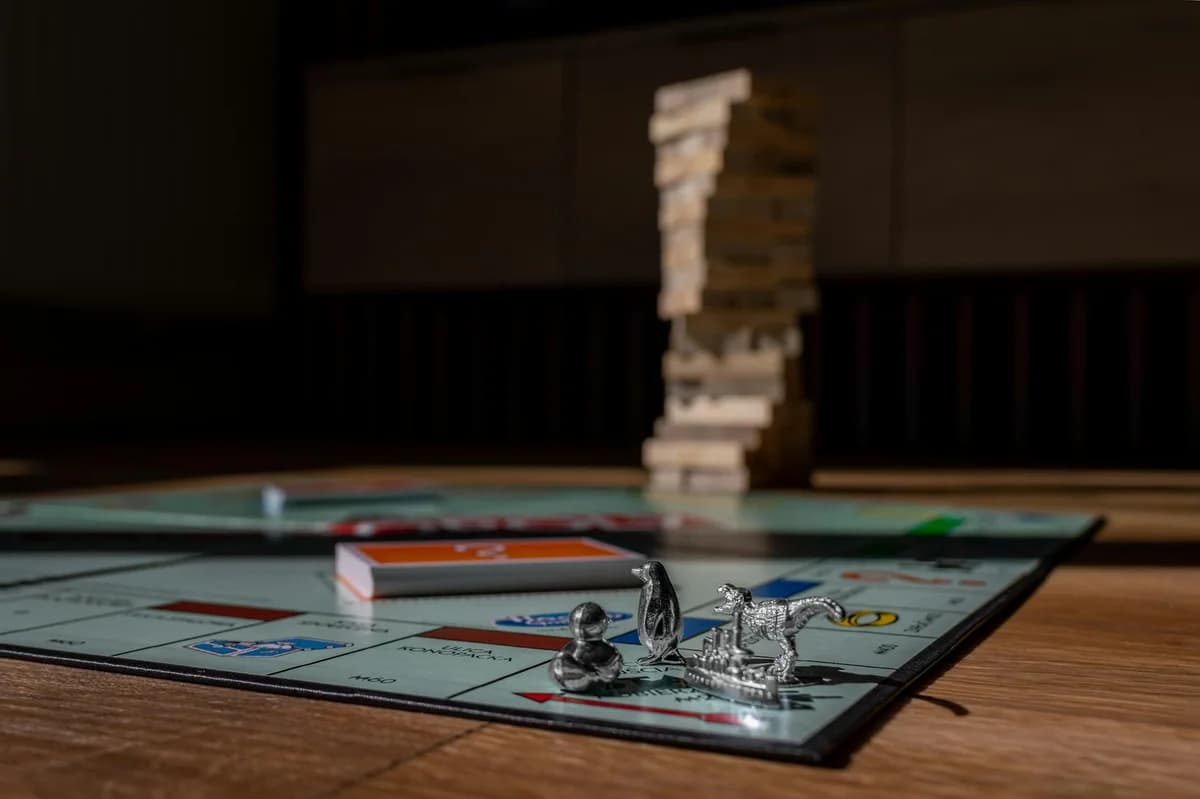 A close-up of a Monopoly board game featuring a silver car token and chance card.