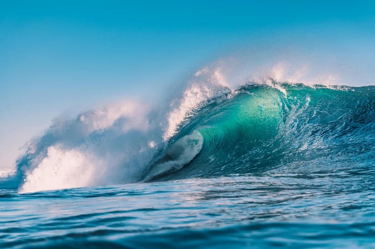 Stunning ocean wave captured in Carcavelos, Lisbon under a clear blue sky.