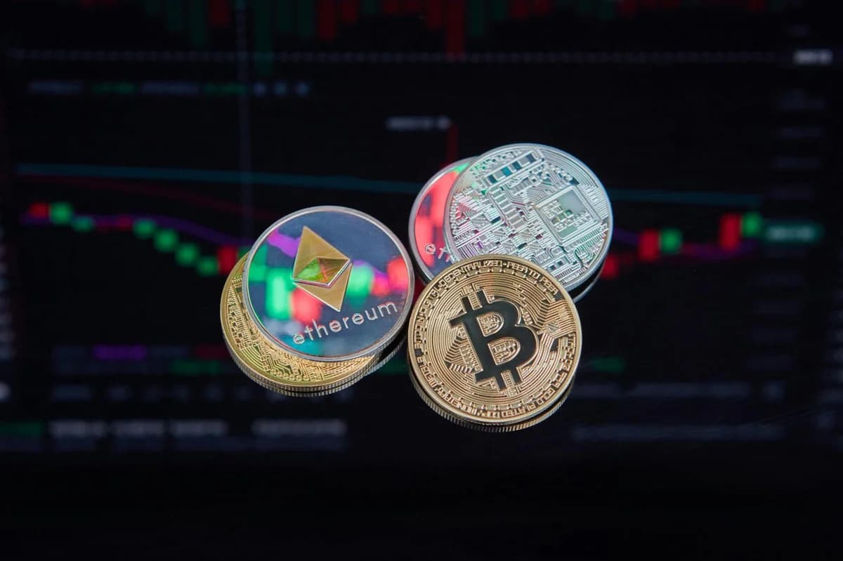 Close-up of Bitcoin coins on a keyboard with a trading chart in the background