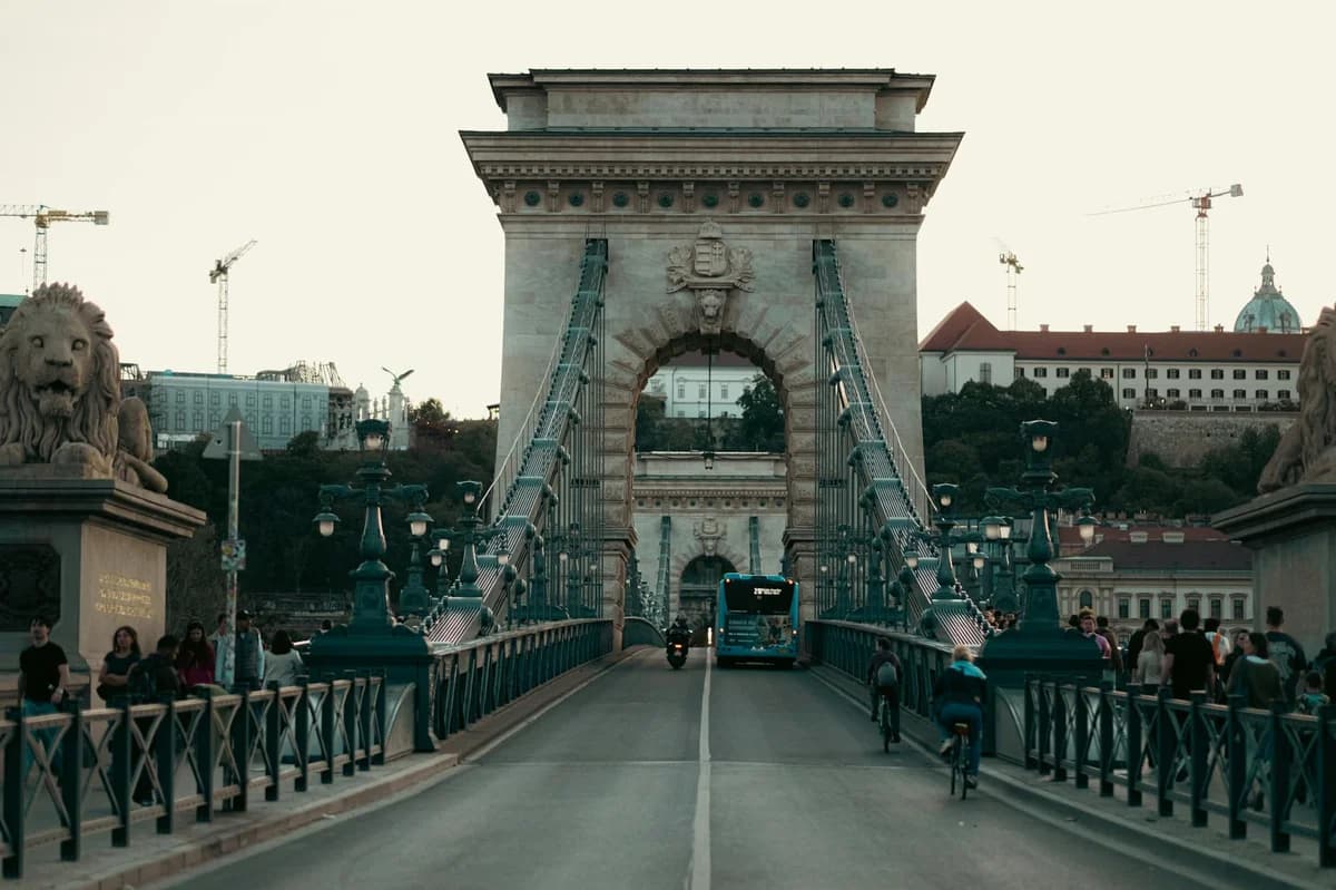View of the Széchenyi Chain Bridge, a historic landmark in Budapest against a dramatic sky.