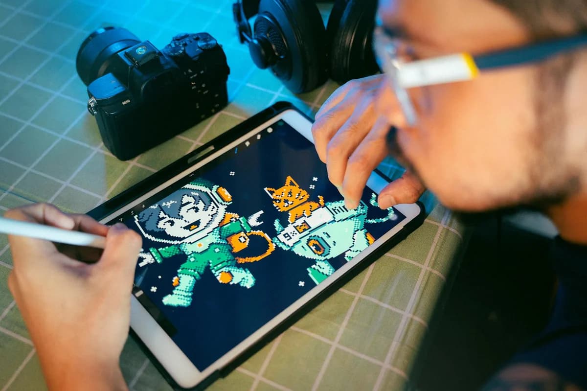 A person working on digital embroidery at a desk with screens and tools.