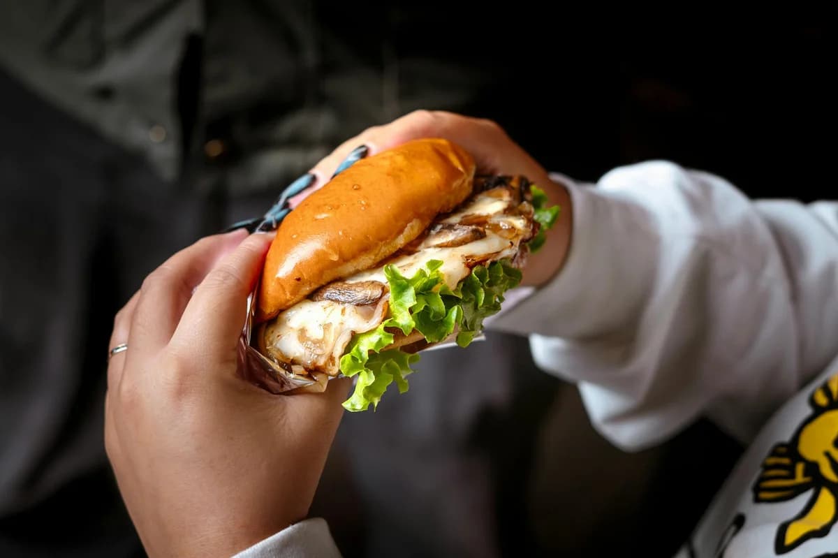 Close-up of a club sandwich with lettuce, tomato, and meat on a yellow background.