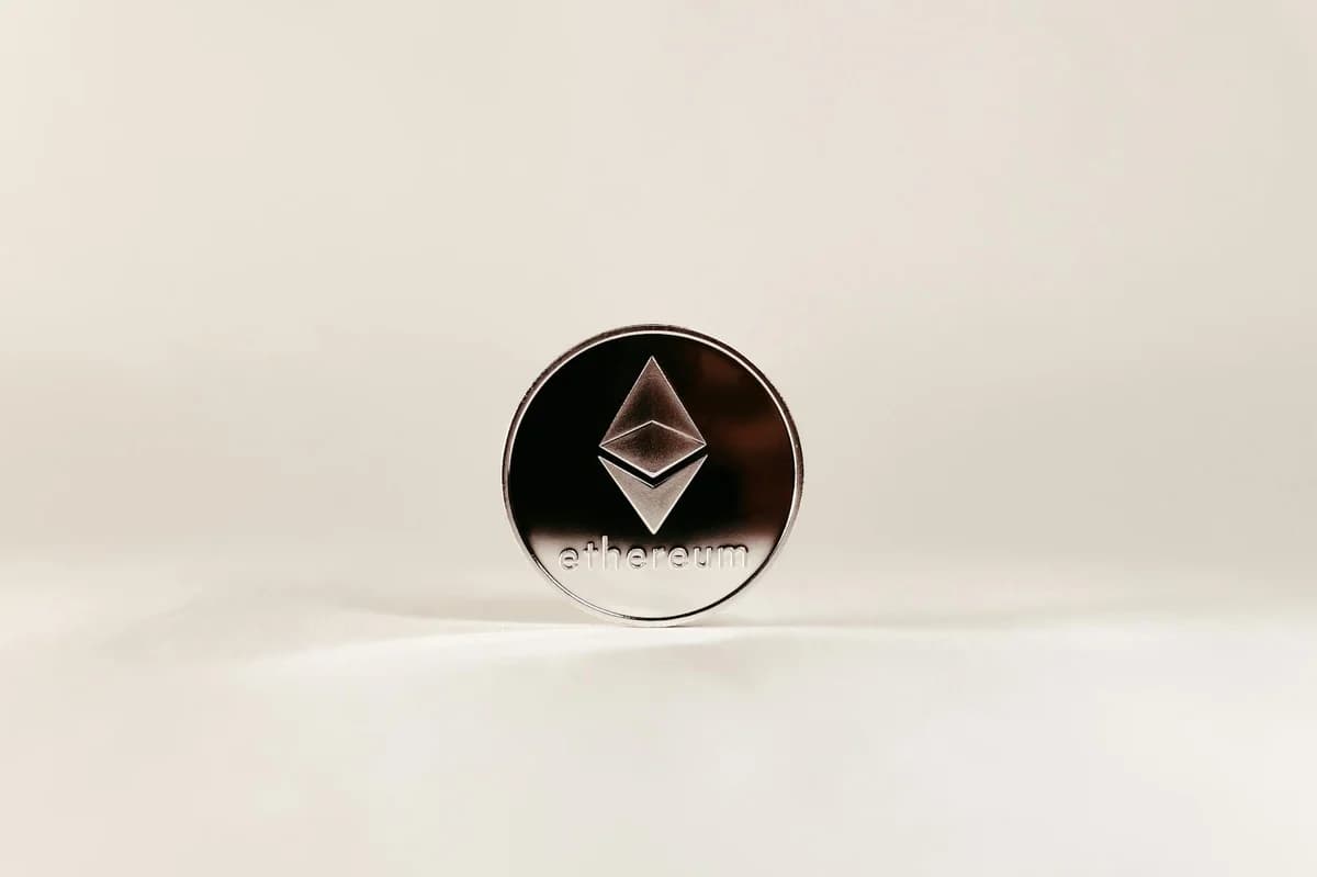 Close-up of a shiny Ethereum coin with a minimalist white background, ideal for finance topics.