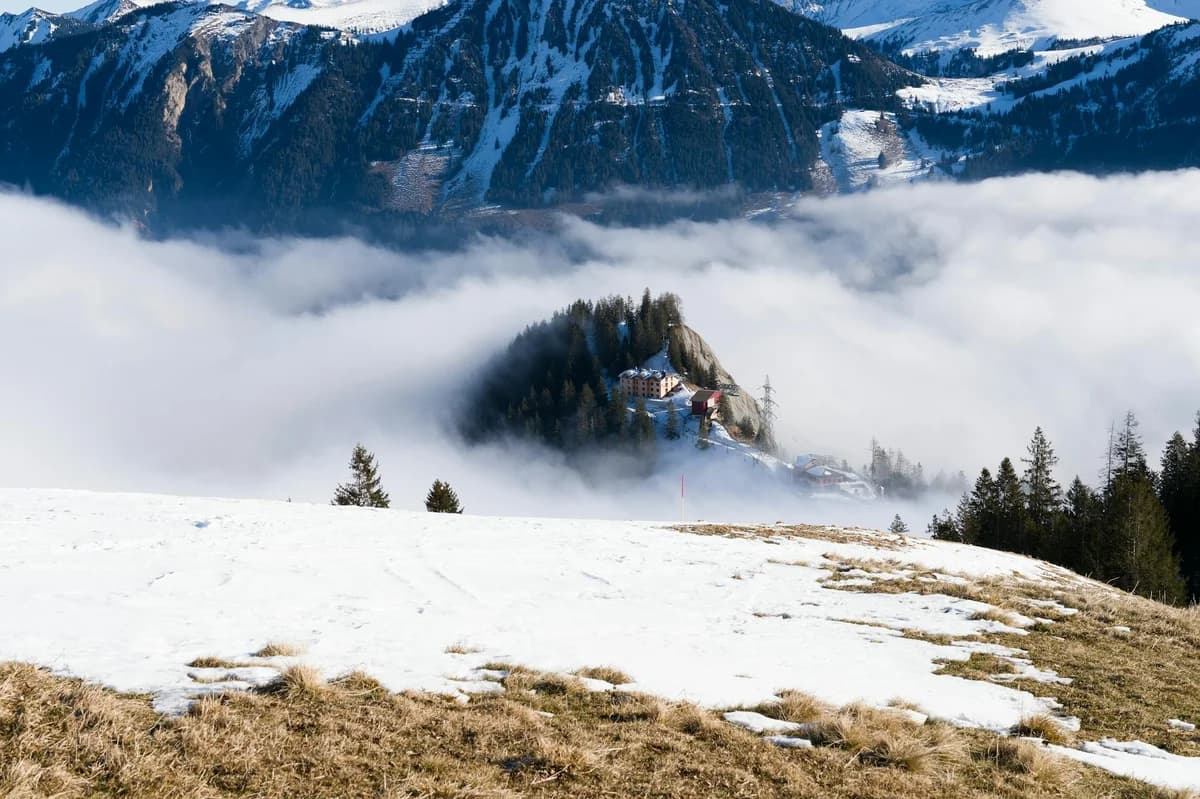 Avalanche warning sign on snowy trail in Swiss Alps with panoramic mountain views.