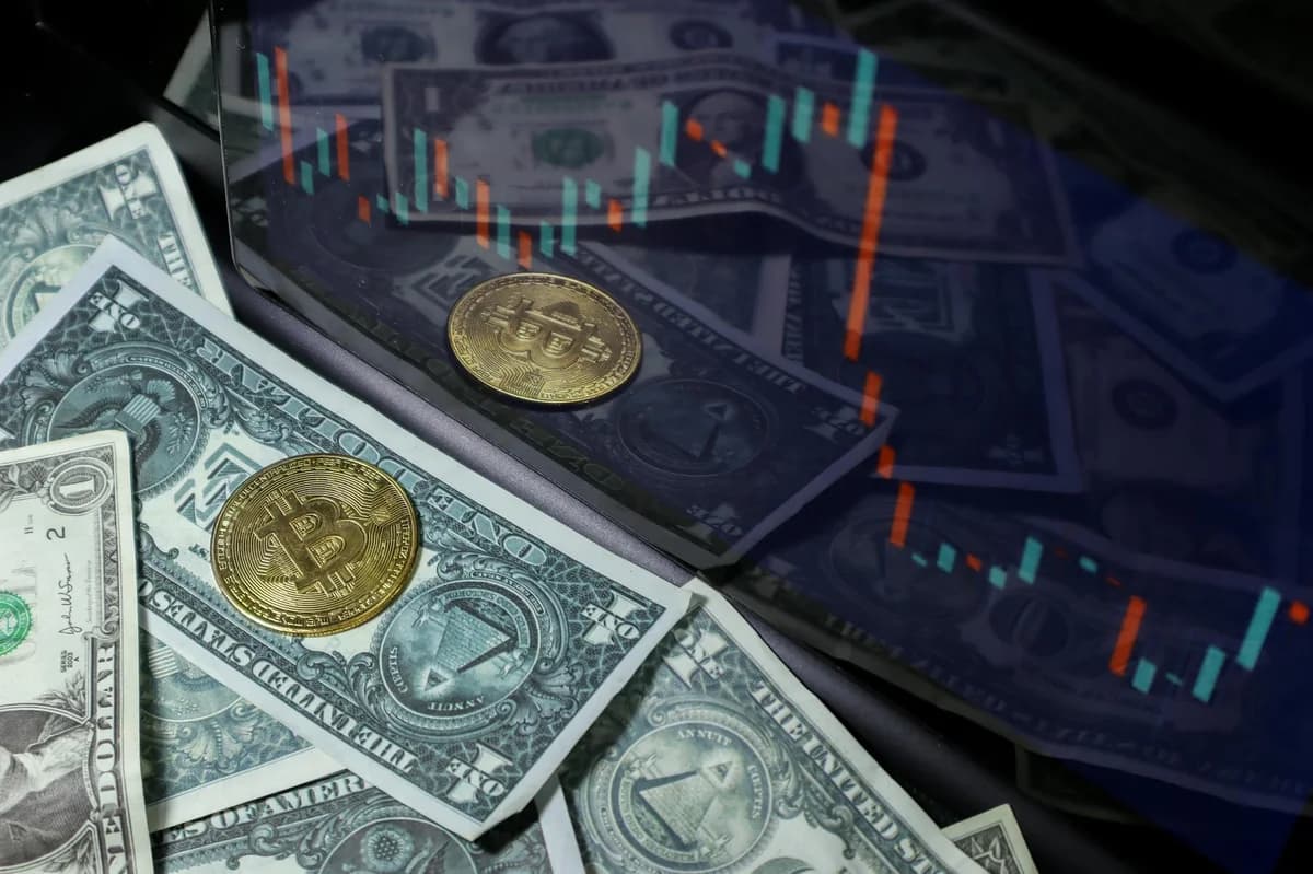 Bitcoin coin resting on a background of various US dollar bills, symbolizing the contrast between traditional and digital currency.