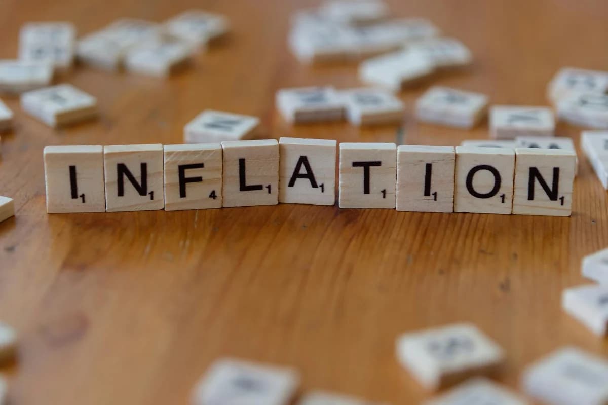 Wooden scrabble tiles arrange to spell 'Food Inflation' on a rustic wooden surface, conceptually depicting rising food prices.